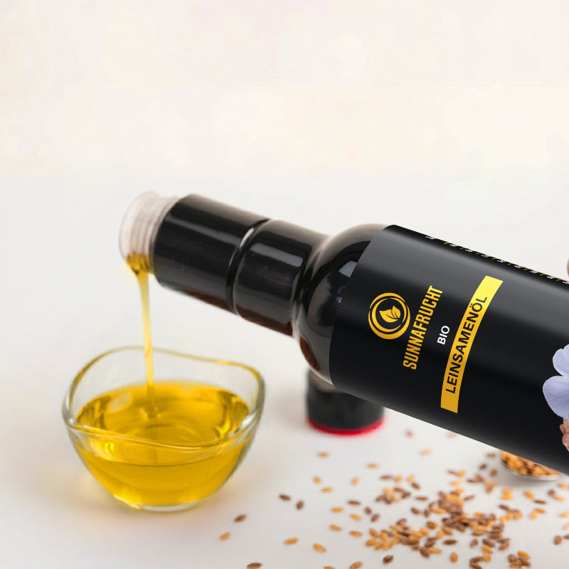 Goldgelbes Bio Leinsamenöl wird aus der Flasche in eine Glasschale gegossen, daneben liegen Leinsamen