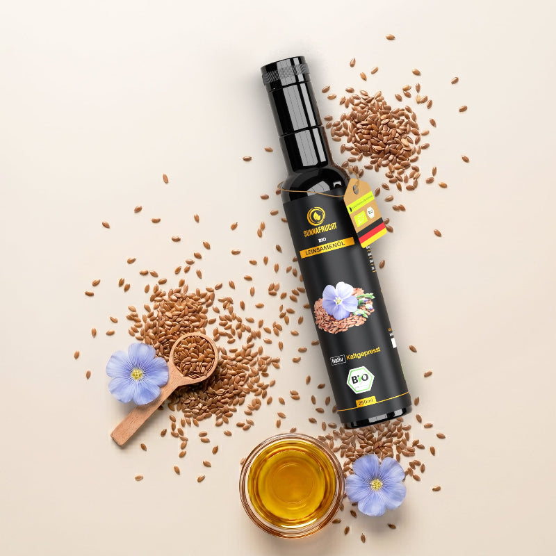 Flatlay Bio Leinsamenöl 250 ml: dunkle Flasche mit Leinsamen, Holzlöffel, blauen Leinblüten und Schale mit Öl