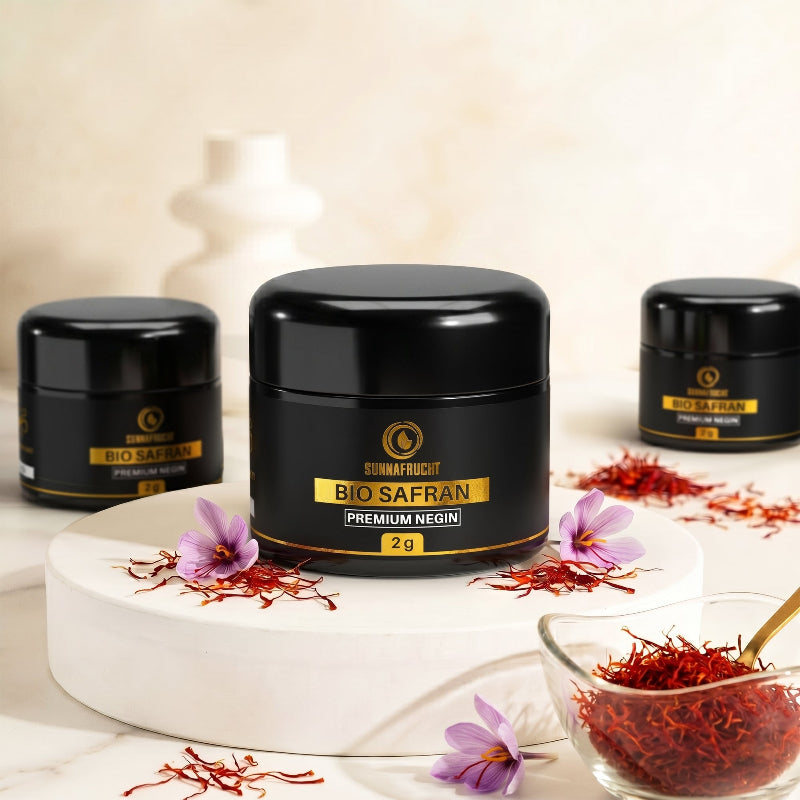 Drei Bio Safran Negin Jars mit roten Fäden und rosa Safranblüten auf weißem Hintergrund