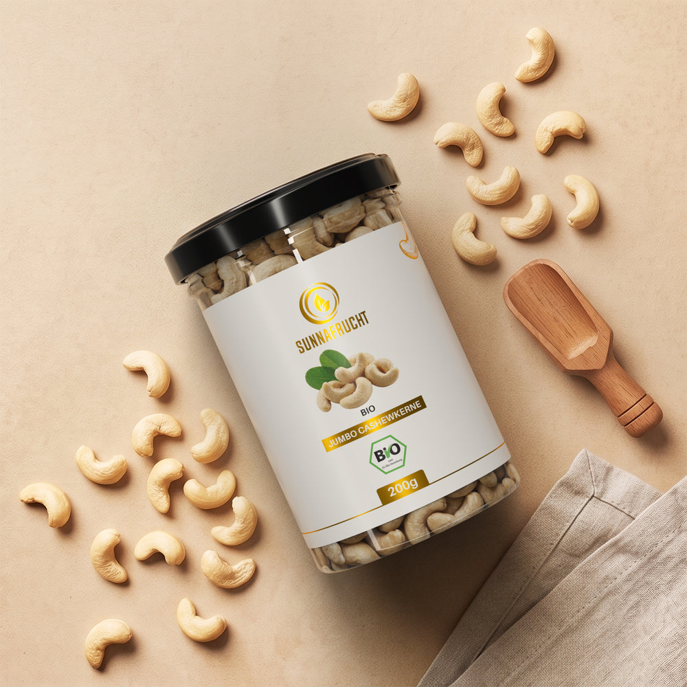 Bio Cashewkerne von oben: liegende Dose zwischen verstreuten ganzen Cashewkernen, Holzschaufel und Leinentuch