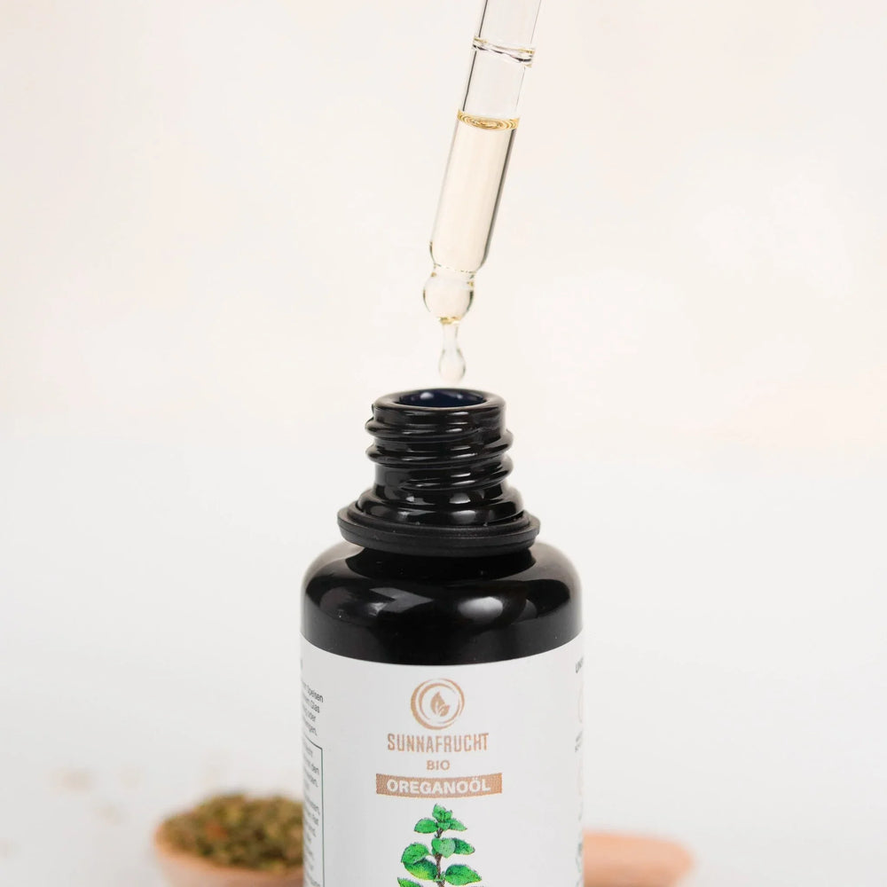 Nahaufnahme einer Flasche Bio Oreganoöl mit Pipette und Tropfen, naturbelassenes Öl
