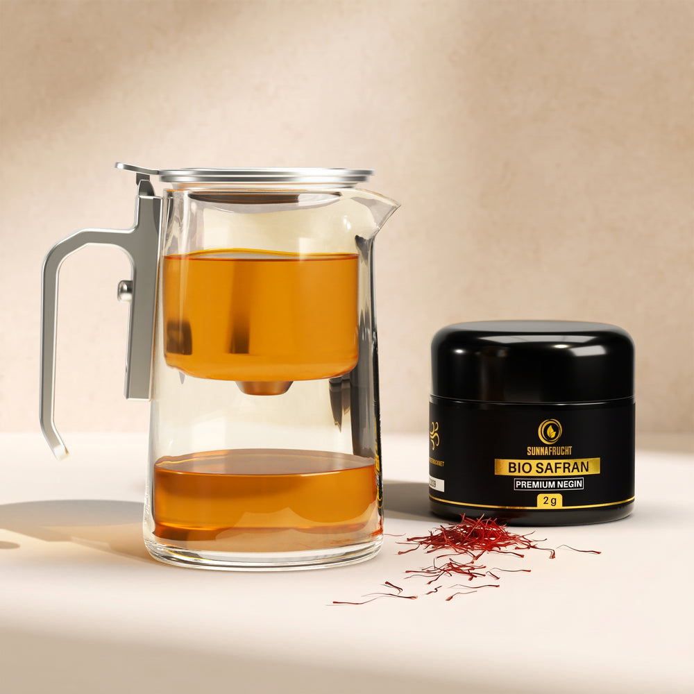 Bio Safran Tee Set: Glasteekanne 600 ml mit Magnetsieb und goldgelbem Aufguss neben Bio Negin Safran 2 g im Violettglas mit Safranfäden